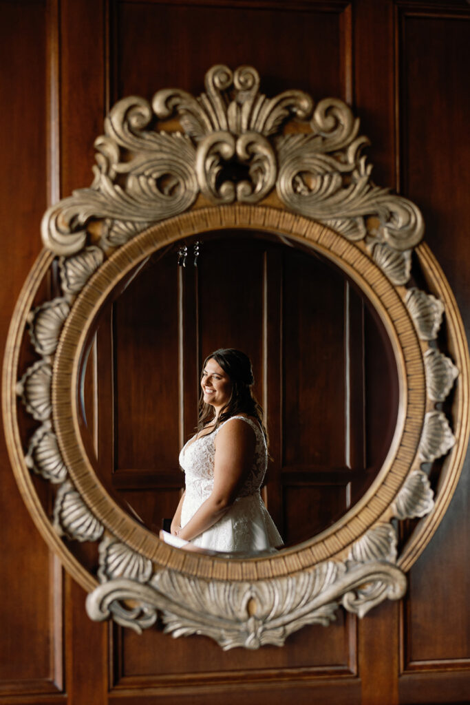 Bride posing in mirror with wedding dress on.
