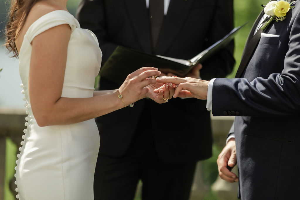 Close up shot by Natalie Marie Photo of bride and groom putting on their rings during the ceremony vows.