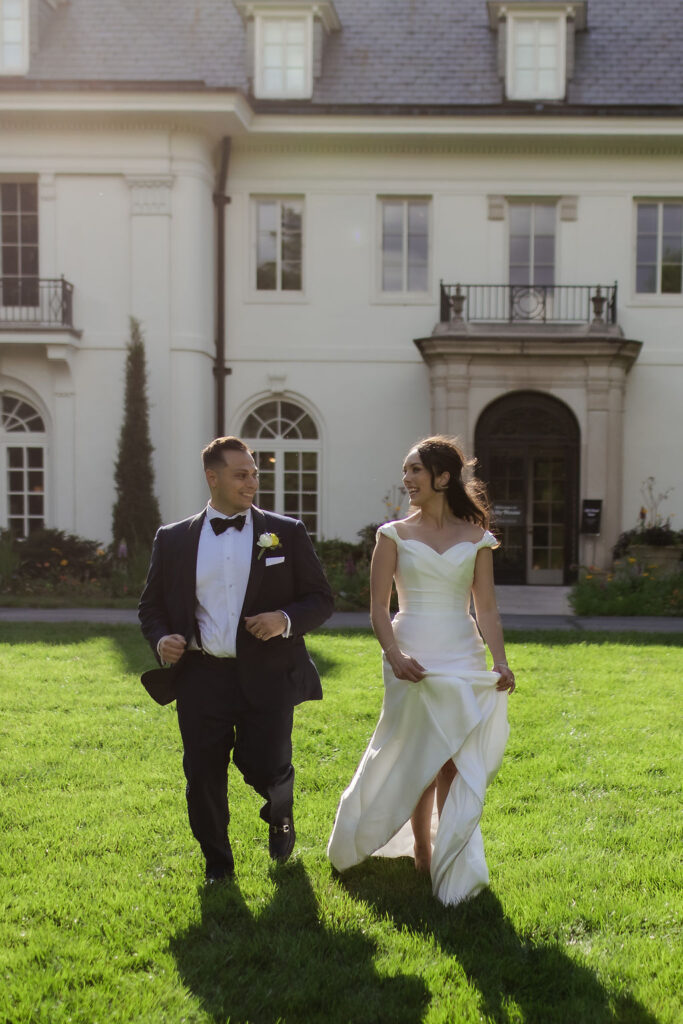 Newly weds running together in front of the lilly house Newfields Indianapolis.