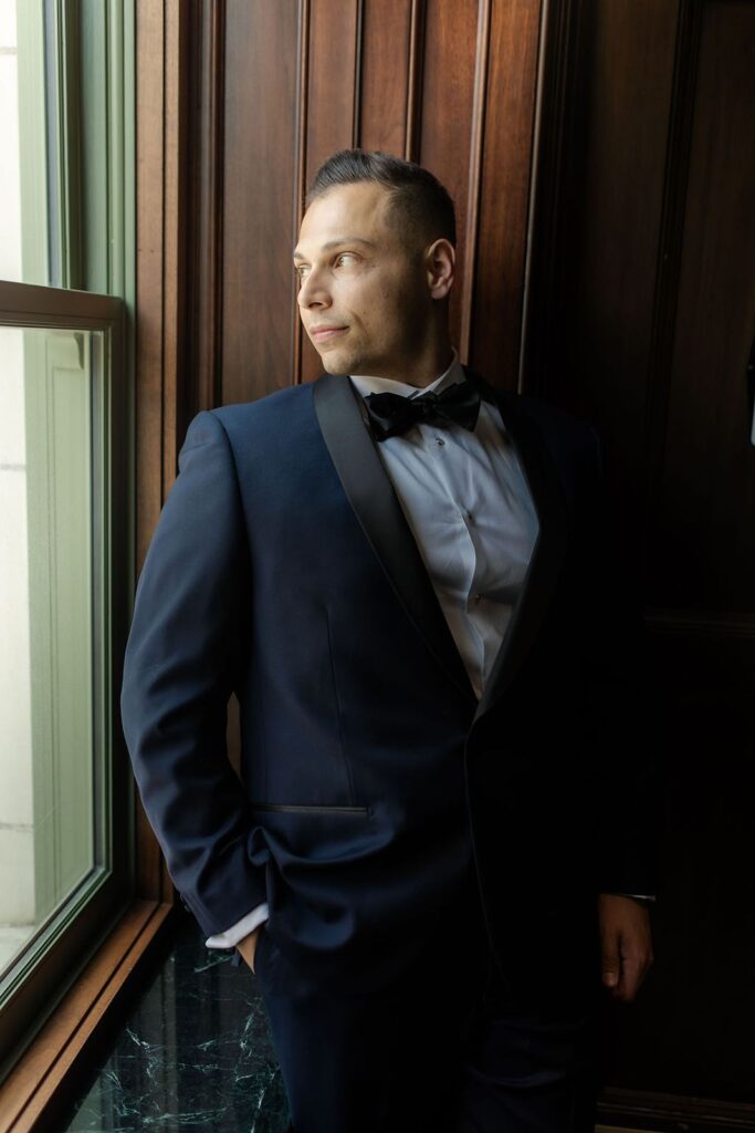 Groom standing in front of window at Bottleworks hotel.