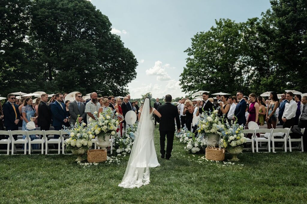Newfields outdoor wedding ceremony of bride walking down the aisle from behind view.
