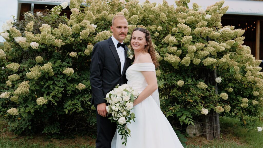 Groom posing with Bride holding her wedding bouquet.
